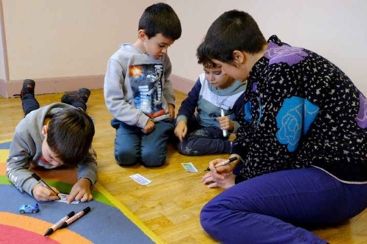 Des jeunes enfants font du dessin accompagnés par une artiste