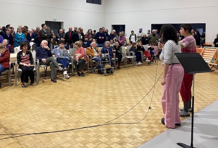 Deux personnes parlent dans un micro face à une assemblée